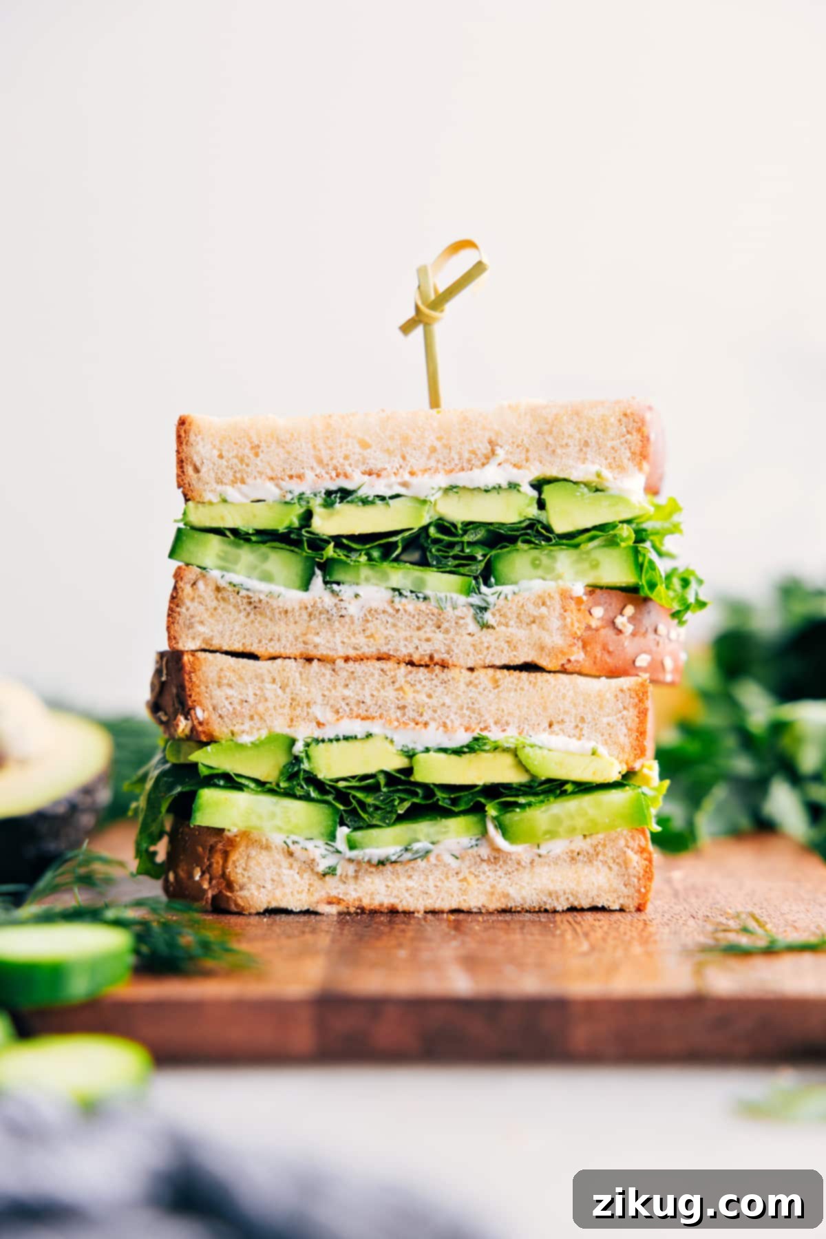 Stacked avocado sandwich halves showing creamy avocado, crisp cucumber, and fresh lettuce, ready to be enjoyed.
