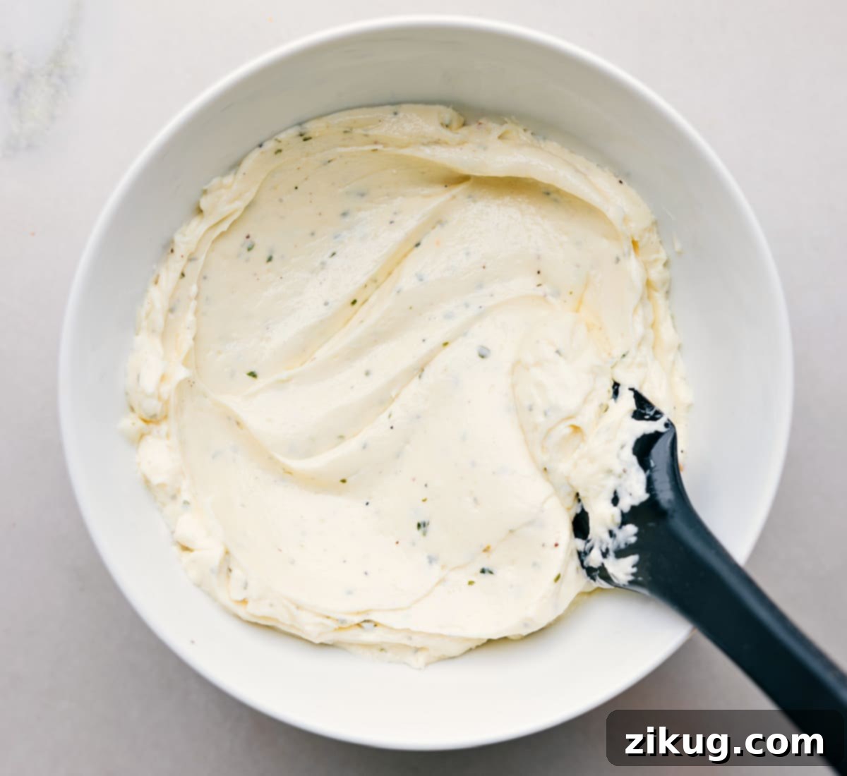 A bowl of creamy herb spread, perfectly mixed and ready to be spread onto the bread for the avocado sandwich.