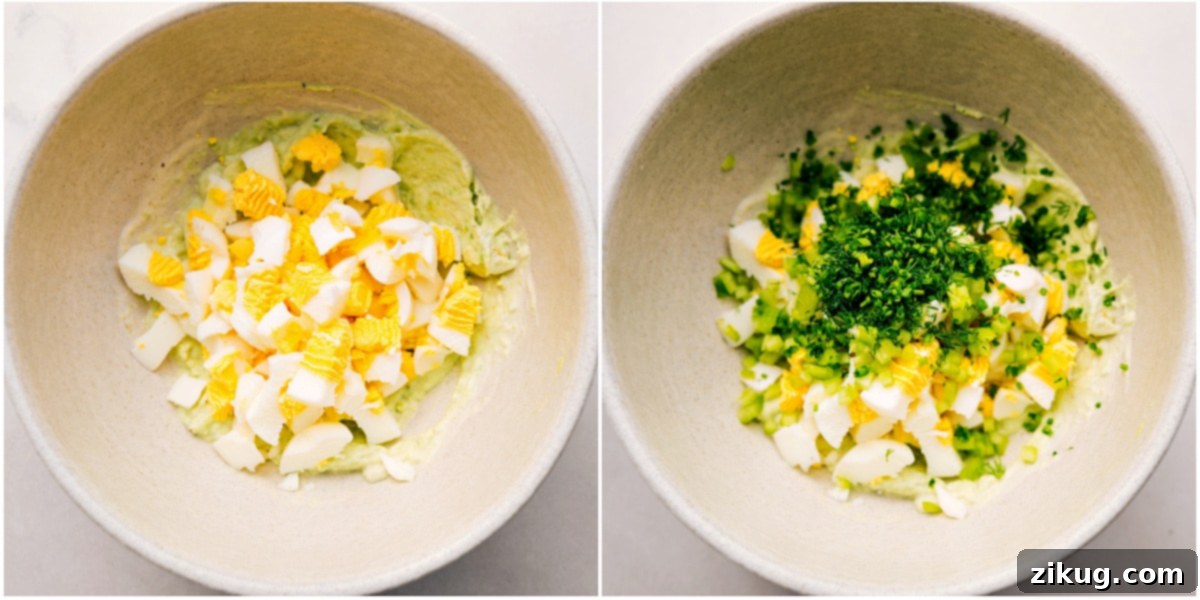 Chopped eggs and fresh herbs are added to the creamy avocado mixture in a bowl, preparing for the final mix.
