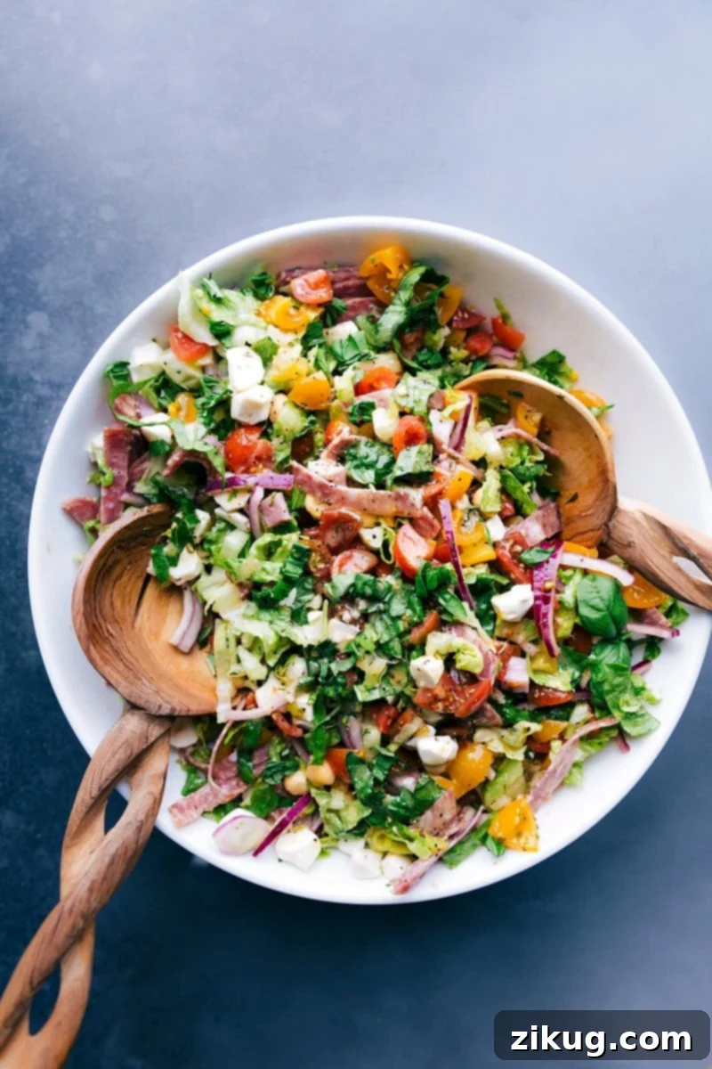 Italian Chopped Salad: Bursting with Colors, Ready to Serve Colorful and vibrant Italian chopped salad with wooden serving spoons in the bowl, ready to be served.