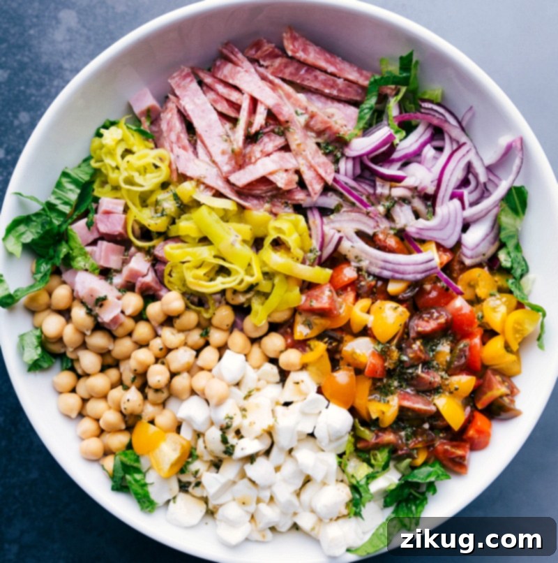 Italian Salad Ingredients: Salami, Veggies, and Chickpeas atop Lettuce Salami, vegetables, and garbanzo beans layered over crisp lettuce, showcasing Italian salad ingredients.