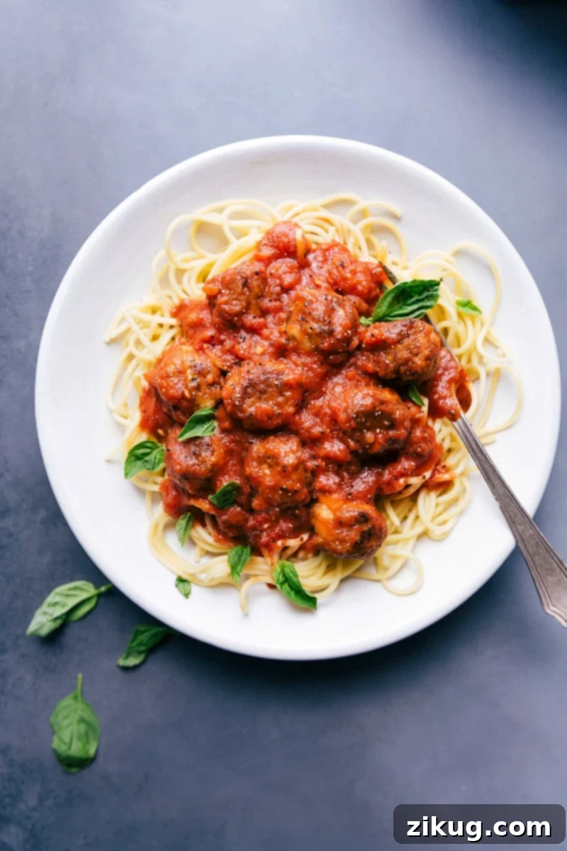 Chicken Parmesan Meatballs with Pasta and Fresh Herb Garnish Chicken parmesan meatballs on a bed of pasta in a delicious red sauce, garnished with fresh herbs.