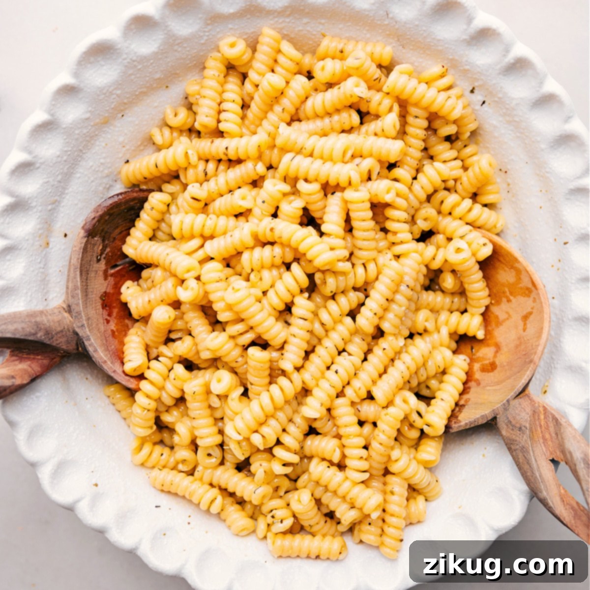 Pasta Gently Coated in Dressing Cooked fusilli bucati pasta lightly tossed with some of the creamy Marry Me Chicken Pasta Salad dressing, ready for chilling.