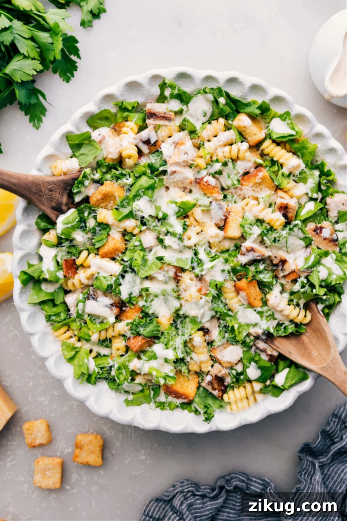 The Best Chicken Caesar Pasta Salad Recipe A vibrant Chicken Caesar Pasta Salad presented in a large bowl, artfully topped with creamy dressing, fresh parmesan shavings, and crisp croutons, indicating it's perfectly prepared and ready to be served and enjoyed by guests.