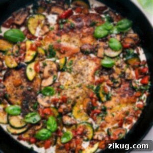 A large skillet filled with creamy chicken and vegetables, garnished with fresh basil, ready to serve.