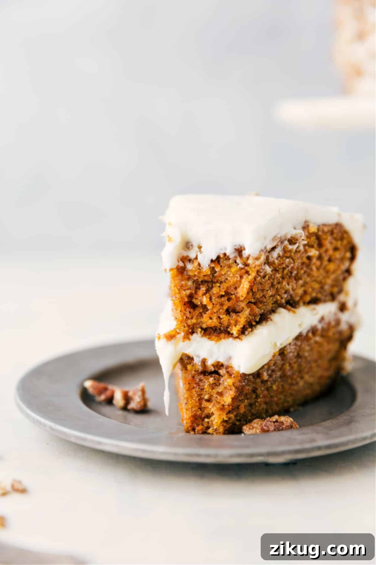 A perfectly baked and artfully frosted carrot cake with a single, inviting slice removed, beautifully showcasing its moist, multi-layered interior, generous cream cheese frosting, and the elegant garnish of optional candied pecans.