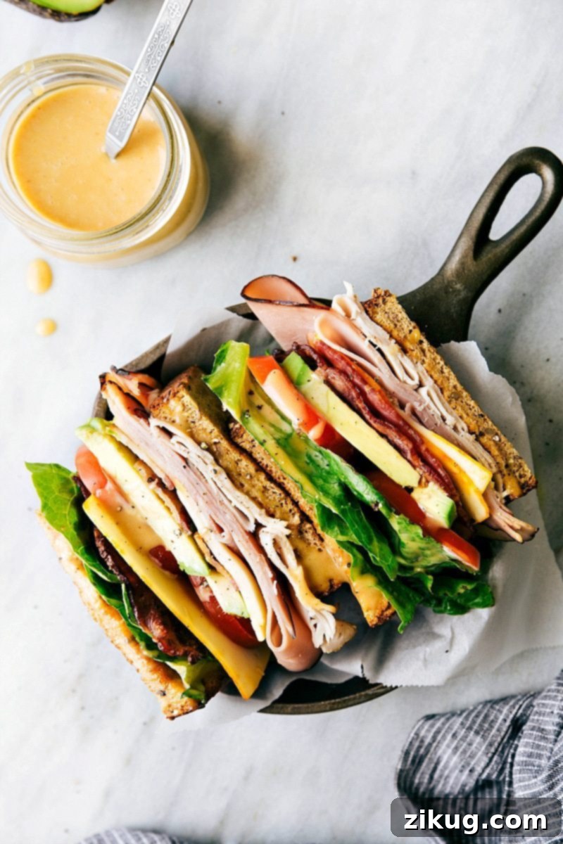 A meticulously prepared Honey Bacon Club Sandwich, showing the vibrant colors of the ingredients and the golden toasted bread.