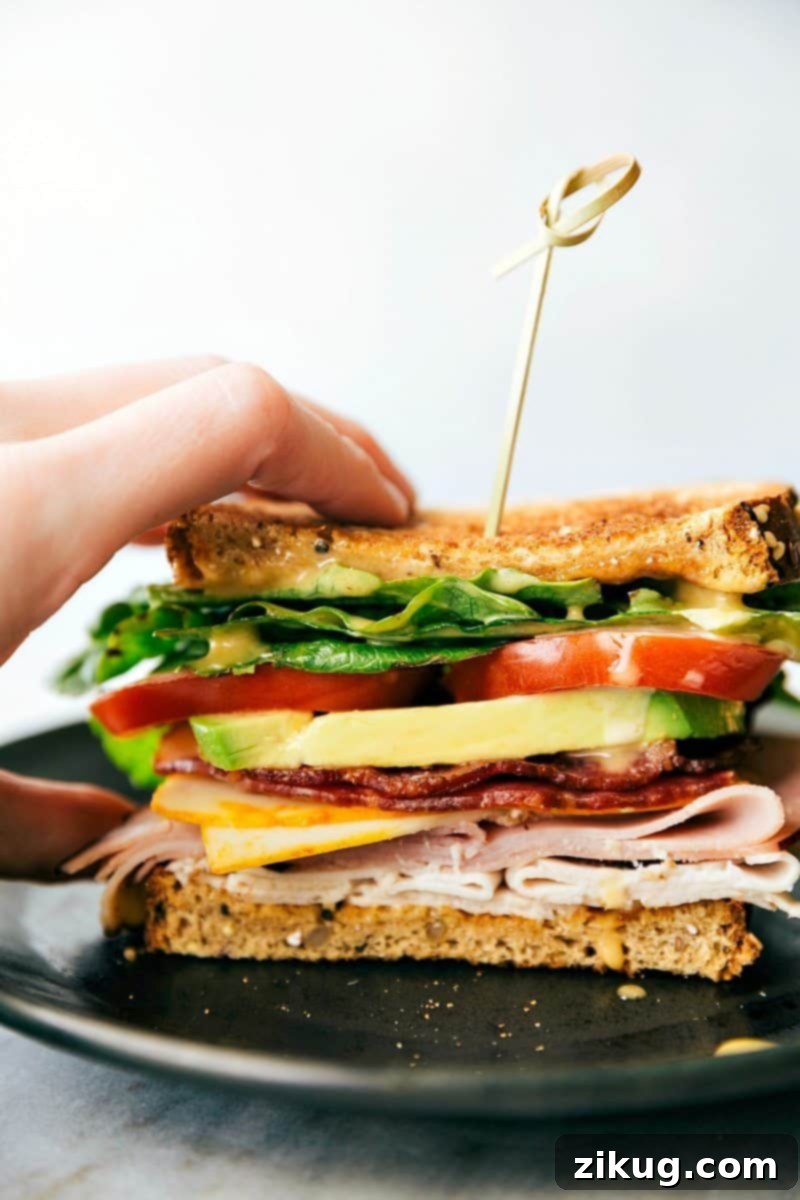 A close-up of the Honey Bacon Club Sandwich sauce being spread on toasted bread, showcasing its creamy texture.