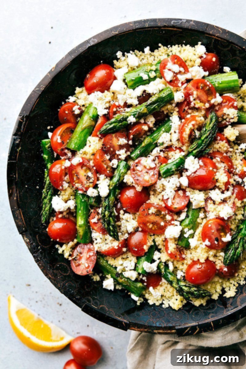 This Asparagus Salad combines crisp roasted asparagus, fresh cherry tomatoes, garlicky couscous, and feta cheese with a simple balsamic vinaigrette. It makes the perfect spring salad that's a hit wherever it's served! Close-up of the delicious Asparagus Salad, ready to be served.