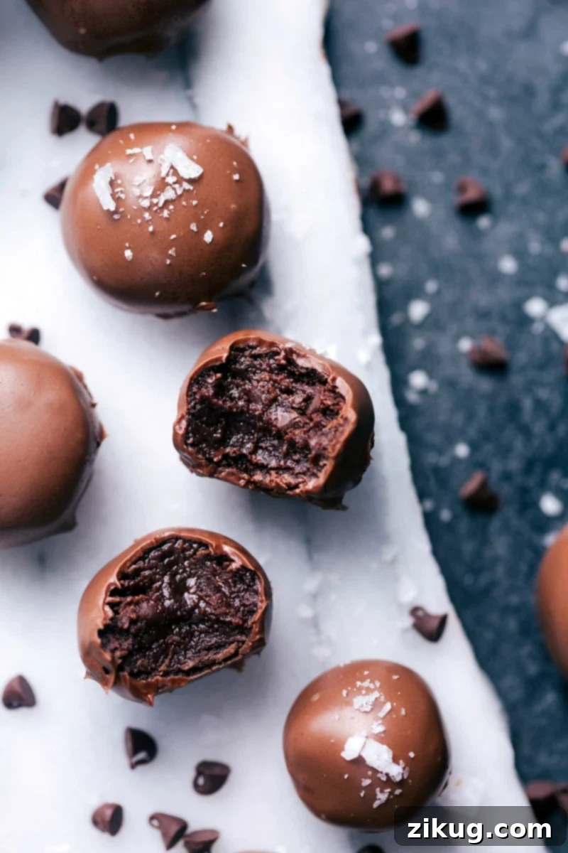These No-Bake Brownie Bites are rich, deeply fudgy, and completely indulgent! The soft, truffle-like filling is dipped in melted chocolate and optionally sprinkled in sea salt (if you like salty-sweet!). Recipe via ChelseasMessyApron #dessert #best #quick #easy #simple #chocolatechip #seasalt #nobake #brownie #bites No-Bake Brownies Bites
