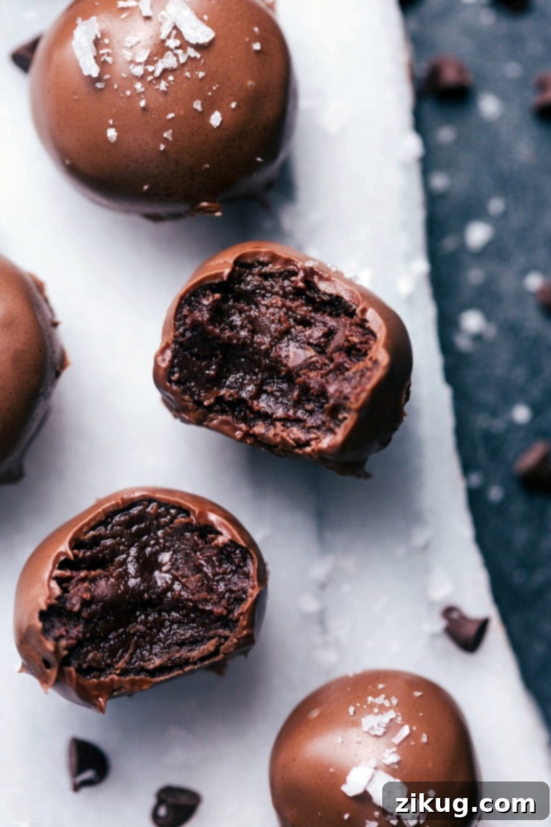 No-Bake Brownie Bites are rich, deeply fudgy, and completely indulgent! The soft, truffle-like filling is dipped in melted chocolate and optionally sprinkled in sea salt. Recipe via ChelseasMessyApron #dessert #best #quick #easy #simple #chocolatechip #seasalt #nobake #brownie #bites No-Bake Brownie Bites