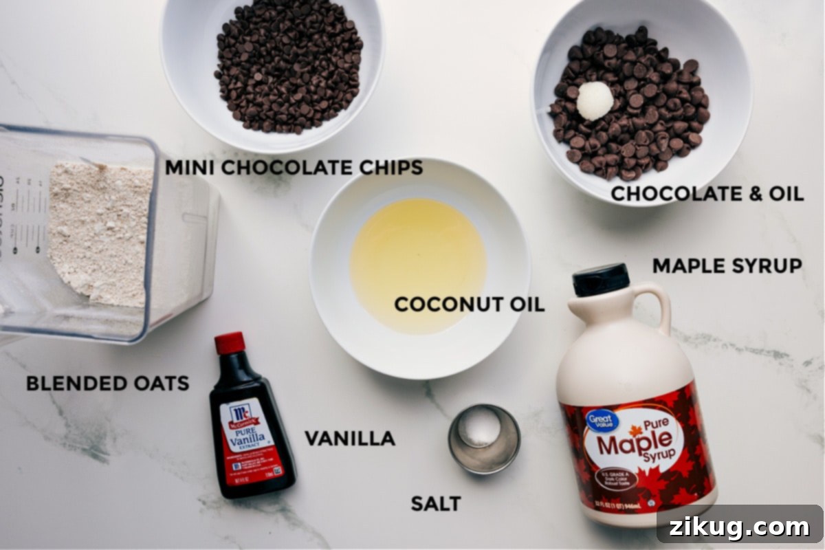 A colorful array of fresh ingredients for homemade Cookie Dough Bark, including vibrant chocolate chips, golden maple syrup, creamy coconut oil, fragrant vanilla extract, fine salt, and wholesome rolled oats, all prepped and ready for easy assembly.