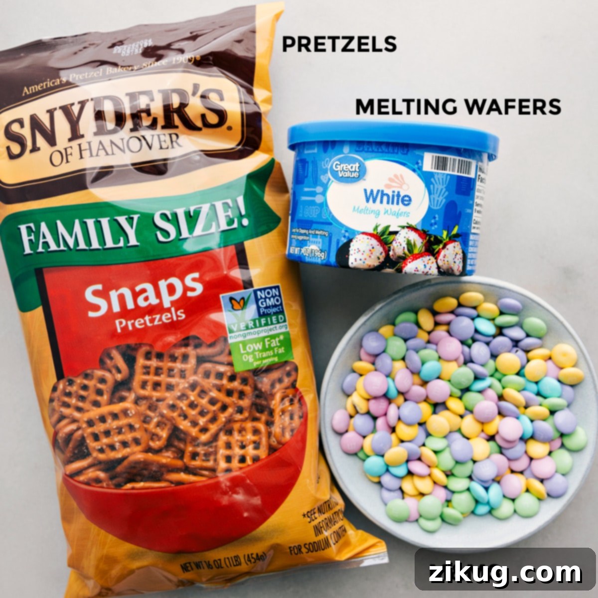 The 3 simple ingredients needed for this recipe: snap pretzels, white candy melts, and pastel M&M's, laid out neatly.