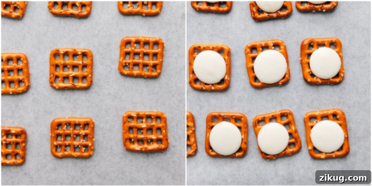 Snap pretzels laid out evenly on a parchment-lined baking sheet with white chocolate melting wafers placed on top of each pretzel, ready for the oven.