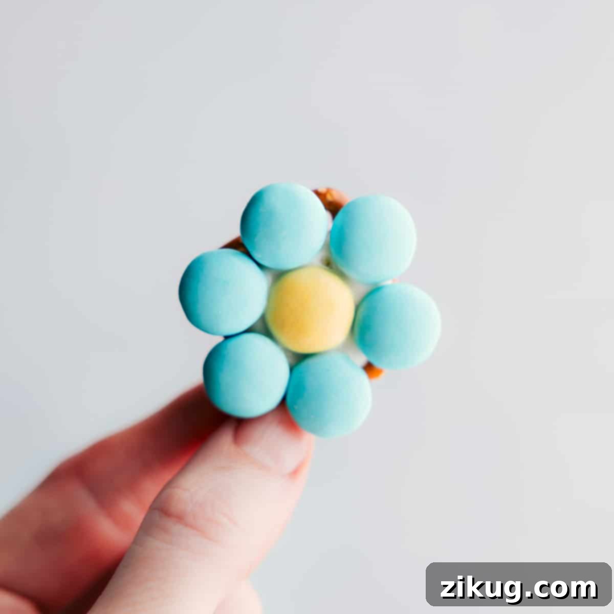 One M&M Flower Pretzel held up, highlighting its simple yet charming design and deliciousness.
