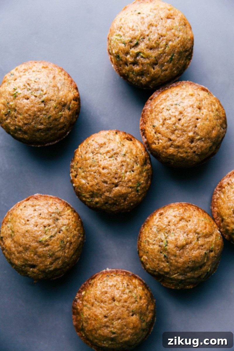 A basket of freshly baked healthy zucchini muffins, golden brown and inviting, with one muffin split open to reveal its fluffy, wholesome interior. Ideal for a nutritious breakfast or a light dessert.