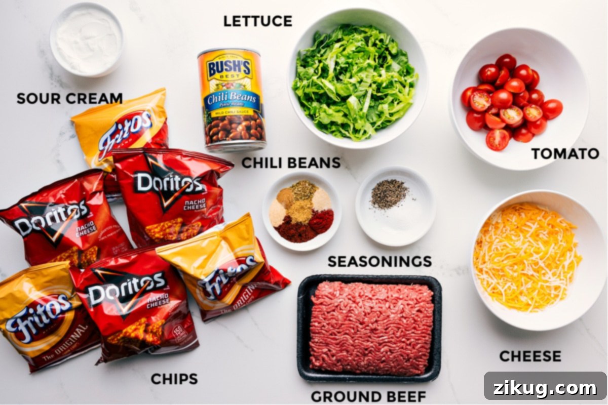 All the essential ingredients for a delicious Walking Taco recipe laid out: sour cream, chili beans, fresh lettuce, juicy tomatoes, shredded cheese, taco seasonings, savory ground beef, and various chip bags.