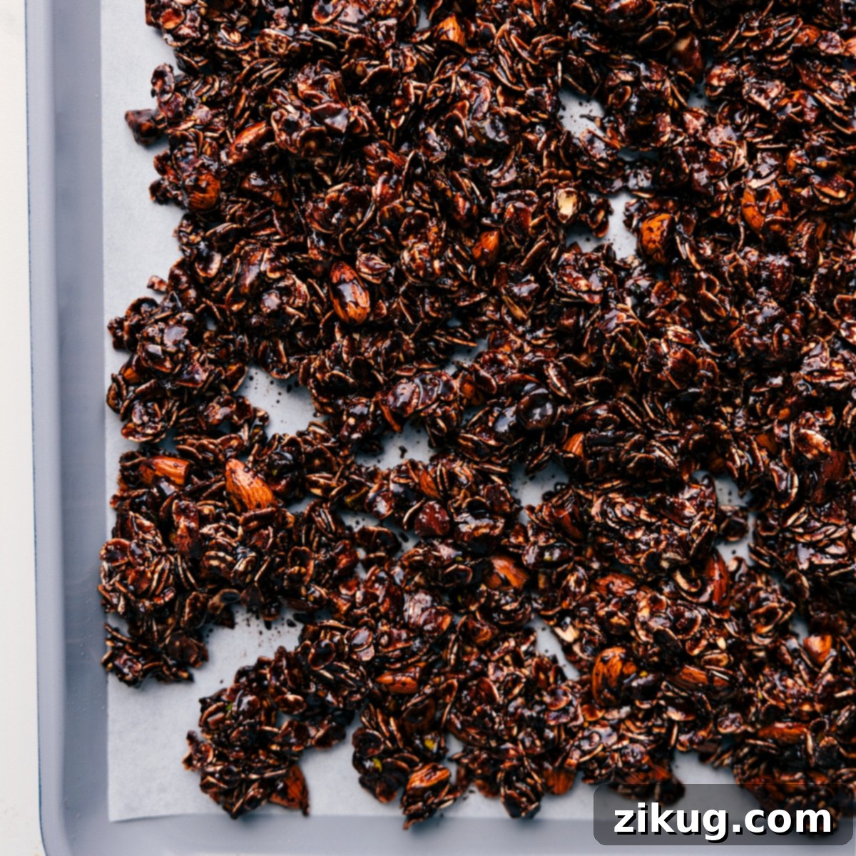 The Perfect Chocolate Granola Recipe Awaits The chocolate granola mixture is evenly spread onto a parchment-lined baking sheet, perfectly ready to be baked to a golden, crunchy perfection.