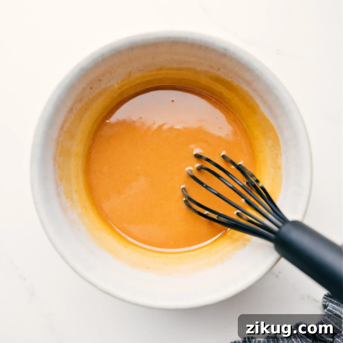 Preparing the Wet Ingredients for Peanut Butter Granola Creamy peanut butter, golden honey, melted coconut oil, fragrant vanilla extract, a pinch of salt, and warm cinnamon being whisked together in a large bowl, creating the wet mixture for this peanut butter granola recipe.