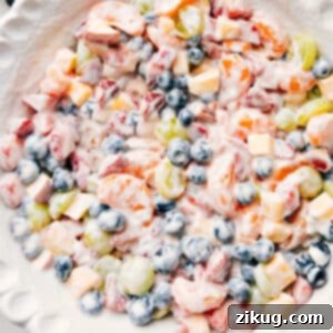 A colorful and delicious fruit salad with creamy yogurt dressing, served in a bowl, capturing the fresh ingredients and appealing presentation.