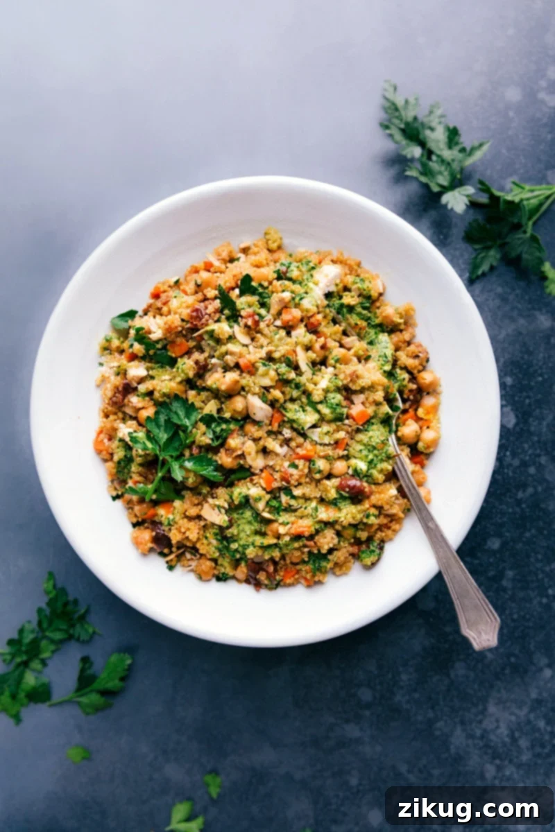 This tasty Quinoa Pilaf is loaded with good-for-you ingredients! Quinoa, chicken, and chickpeas form the protein-packed base. We add lots of veggies and an incredible lemon-herb sauce to finish it off. Healthful, hearty, and so much flavor! Recipe via chelseasmessyapron #healthy #quick #easy #best #protein #dinner #side #thanksgiving #quinoa #pilaf Overhead image of Quinoa Pilaf in a large serving bowl, garnished with fresh herbs and lemon wedges.