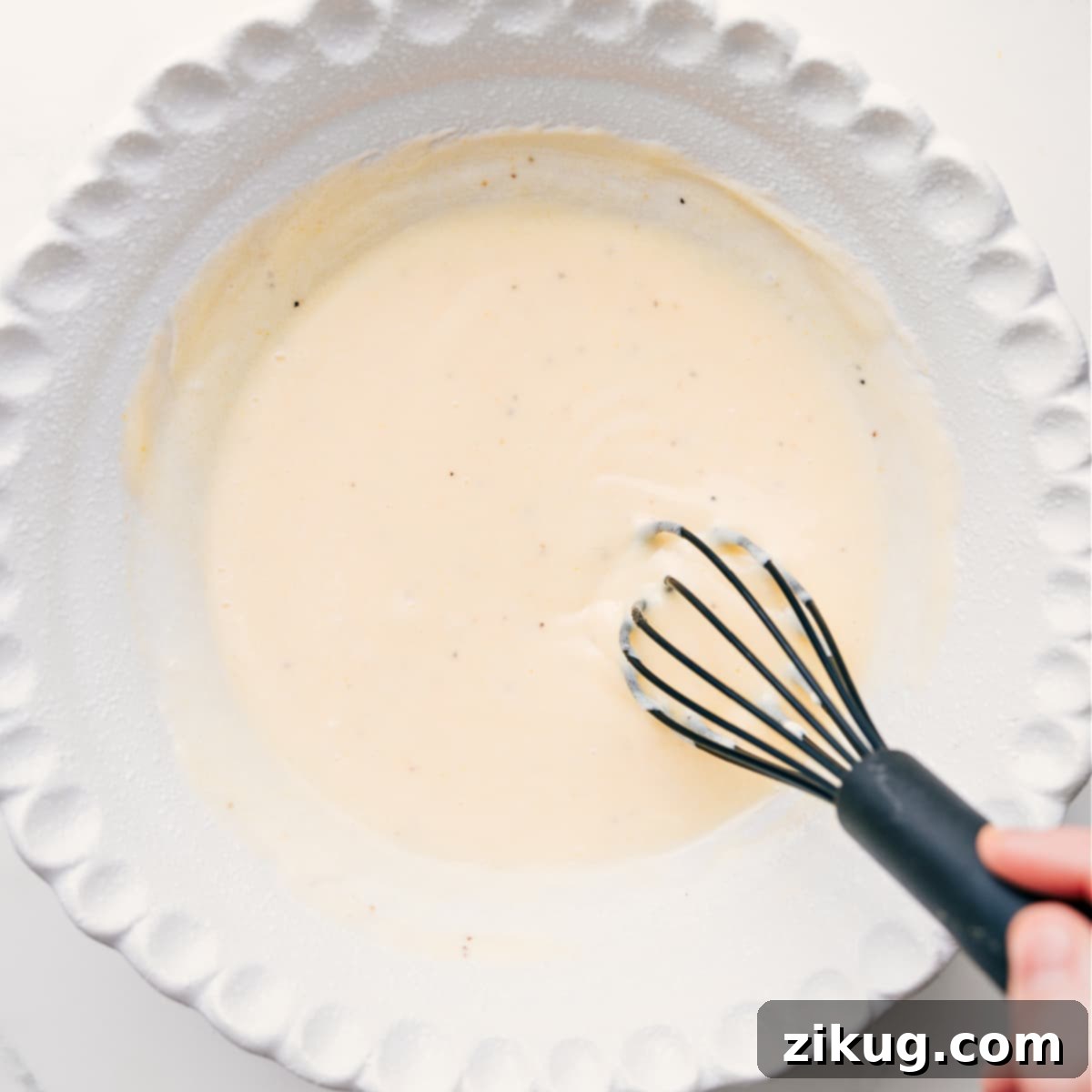 The Best Dressing In A Coleslaw The smooth and creamy Chick-fil-A coleslaw dressing being thoroughly whisked in the bottom of a bowl, showcasing its rich texture.