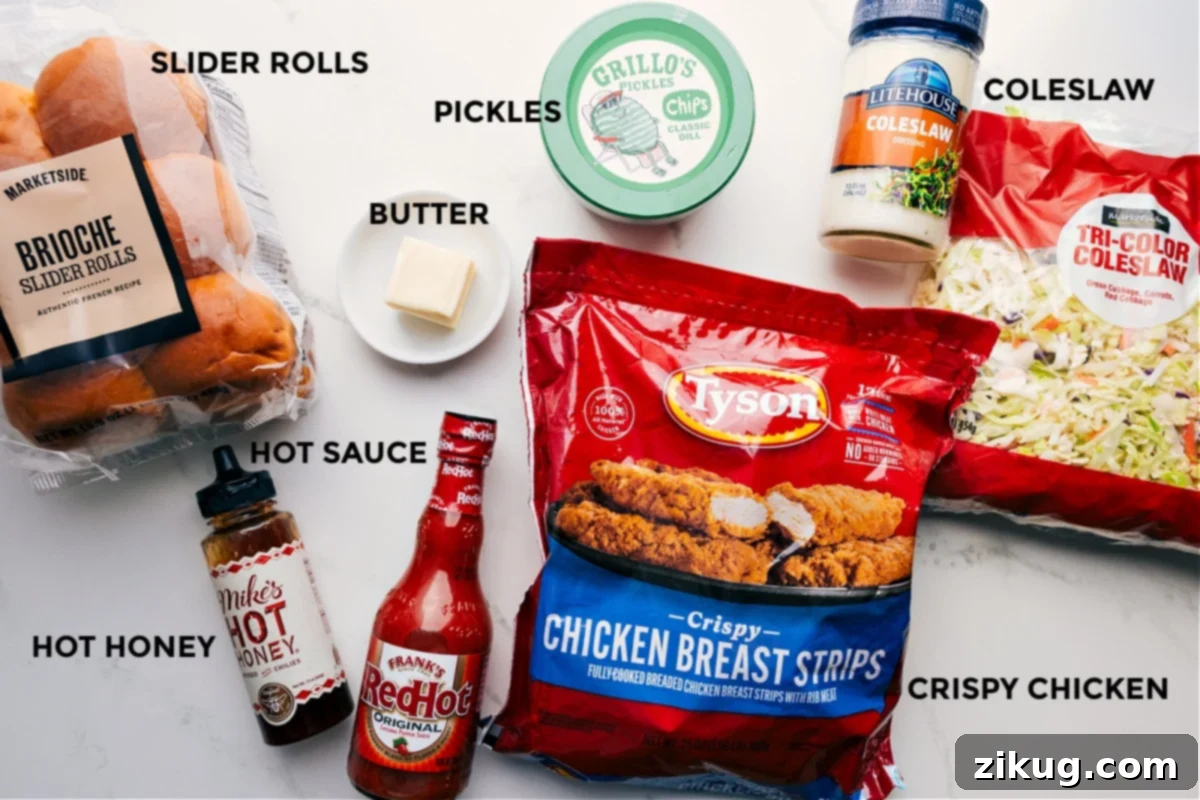 A vibrant display of fresh ingredients for Hot Honey Chicken Sliders, including soft brioche buns, golden crispy chicken, a bowl of seasoned coleslaw, hot sauce, honey, butter, and tangy pickles.