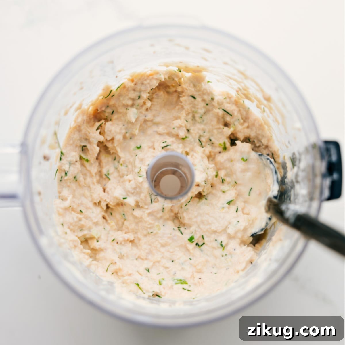 All the ingredients blended together in the food processor to make the creamy tunacado filling, showing a light, airy texture with flecks of green herbs.