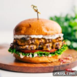 Close-up of a Crack Burger showing its components: patty, melted cheese, bacon, and sauce.