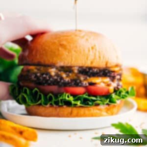 A beautifully assembled smash burger on a plate, showcasing its melted cheese, fresh toppings, and toasted bun, ready to be served.