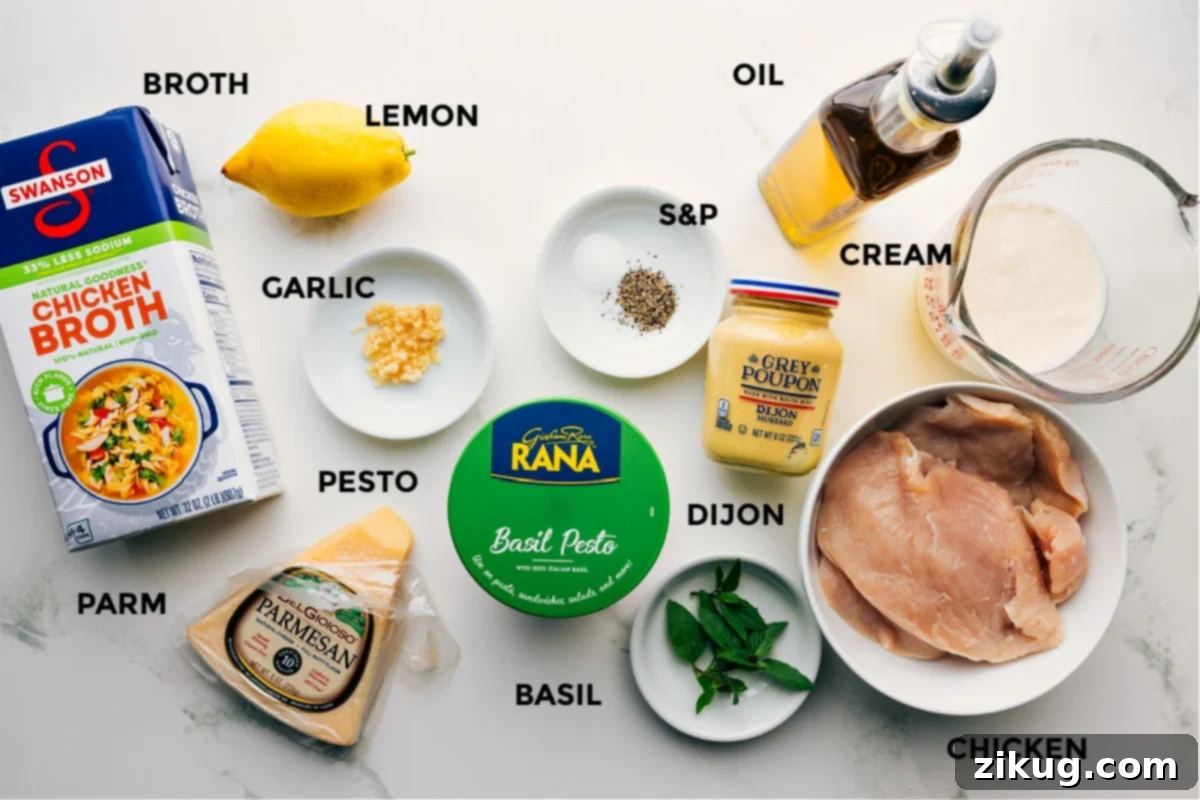All the essential ingredients for Creamy Pesto Chicken laid out, including chicken breasts, chicken broth, heavy cream, fresh basil, Parmesan cheese, basil pesto, olive oil, butter, minced garlic, Dijon mustard, and a lemon.