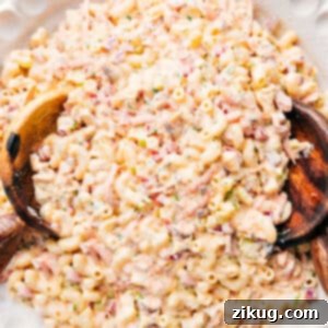 A close-up of a serving of Creamy Chicken Macaroni Salad, showcasing the texture of the macaroni, diced chicken, and colorful vegetables coated in a rich dressing.
