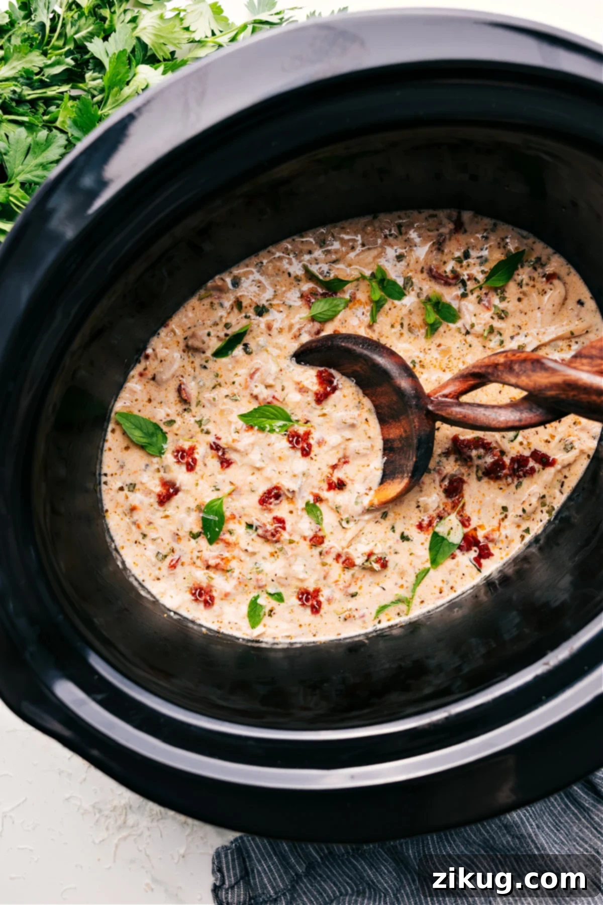 Crockpot Marry Me Chicken in a slow cooker, ready to be served, garnished with fresh basil.