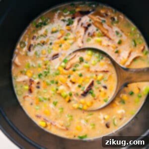 Creamy Homemade Chicken Corn Soup 4 A bowl of Chicken Corn Soup garnished with fresh green onions and a drizzle of sesame oil, ready to be served.