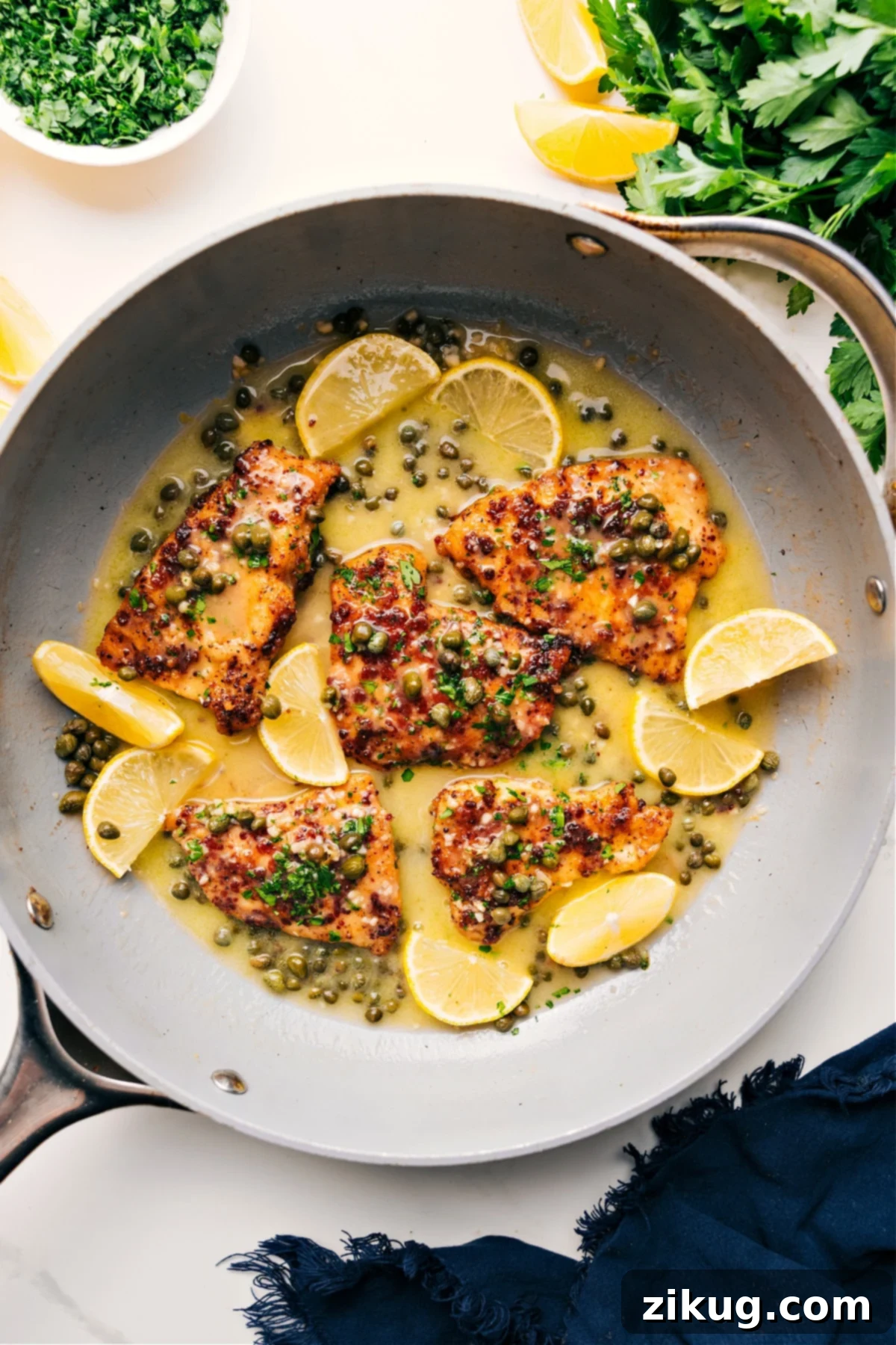 Crispy Chicken Piccata in a skillet with a luscious lemon butter caper sauce and fresh lemon slices, ready to be served.