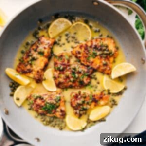 A finished plate of Chicken Piccata with sauce and garnishes.