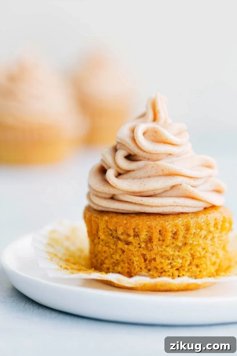 Pumpkin Cupcake With Pumpkin Spiced Cream Cheese Frosting A perfectly baked, moist pumpkin cupcake, generously adorned with a decadent swirl of frosting, eagerly awaiting to be savored as part of our pumpkin spice desserts collection.