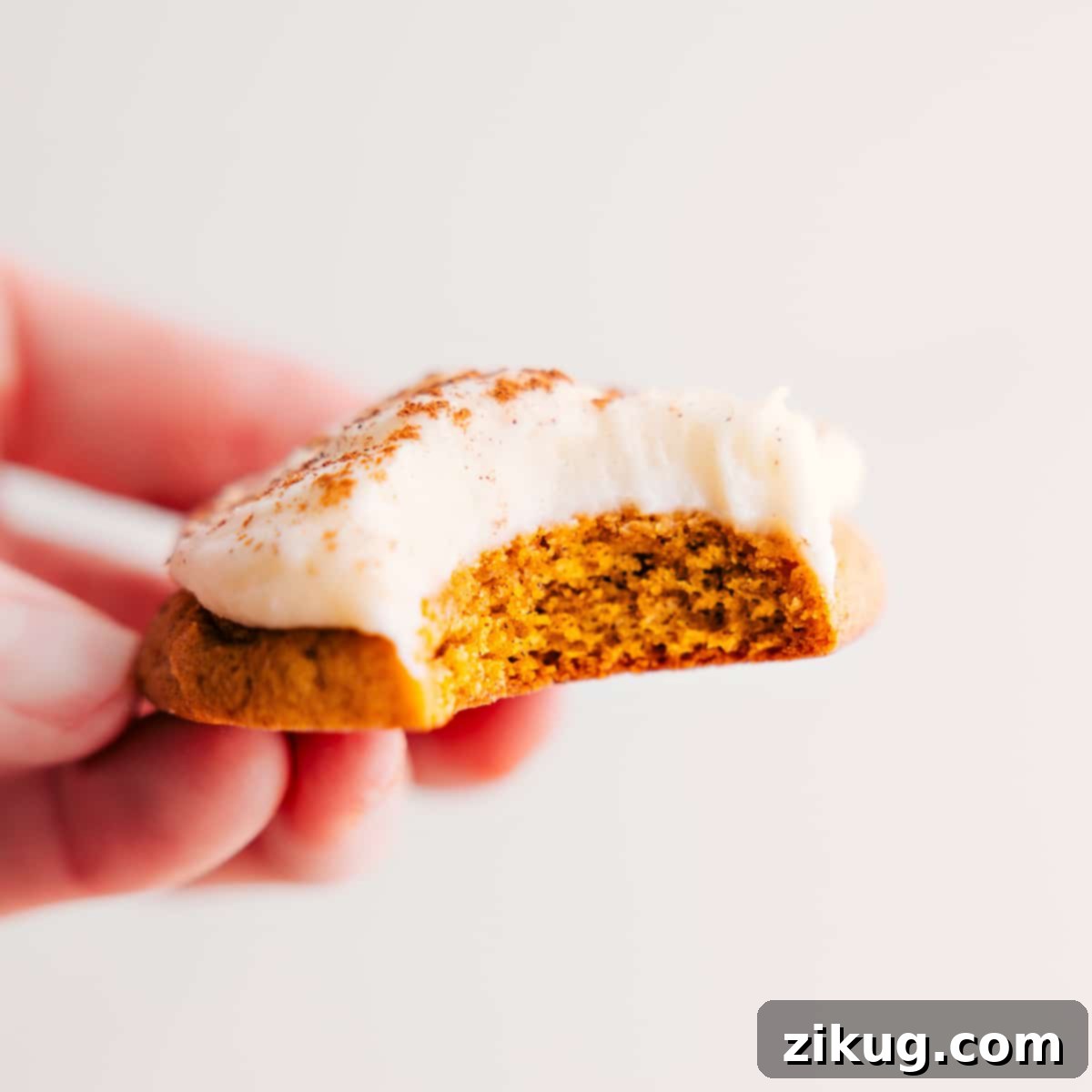 Pumpkin Cookies Topped With The Best Cream Cheese Frosting A perfectly soft pumpkin cookie, generously topped with creamy cream cheese frosting, with a delightful bite taken out.