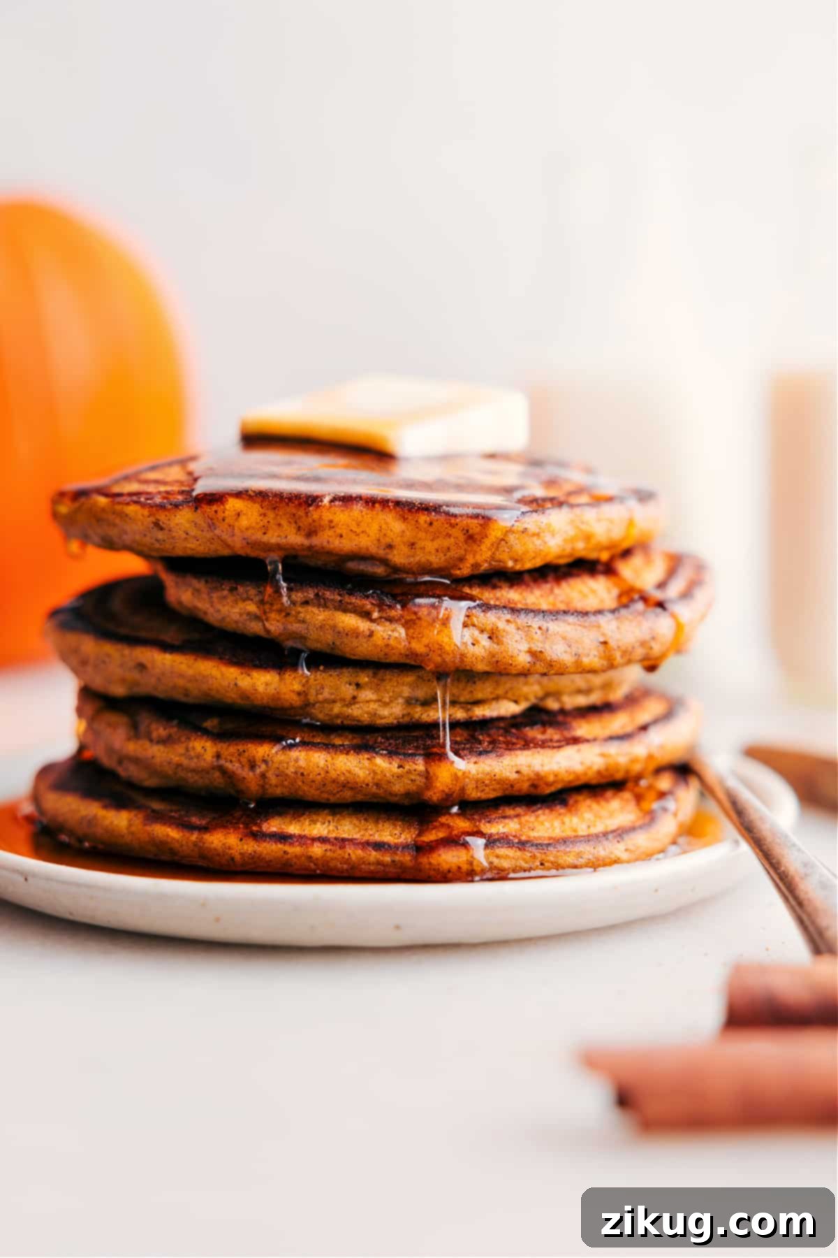 Start Your Fall Mornings With Pumpkin Pancakes A delightful stack of fluffy pumpkin pancakes, generously topped with a pat of melting butter and drizzled with golden syrup, perfect for a cozy fall breakfast.