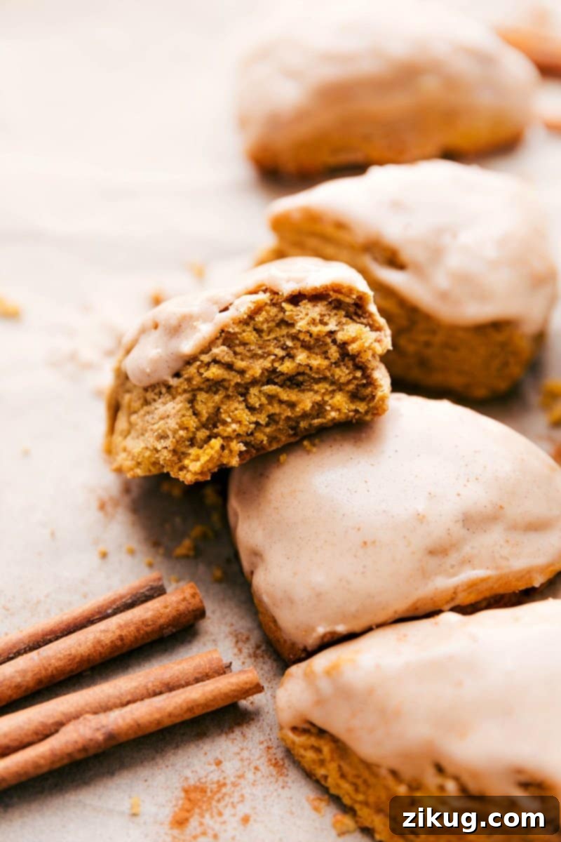 Pumpkin Scones With A Pumpkin Glaze Delightful pumpkin scones, beautifully glazed, with one revealing its fluffy interior after a bite, a perfect pumpkin spice dessert.