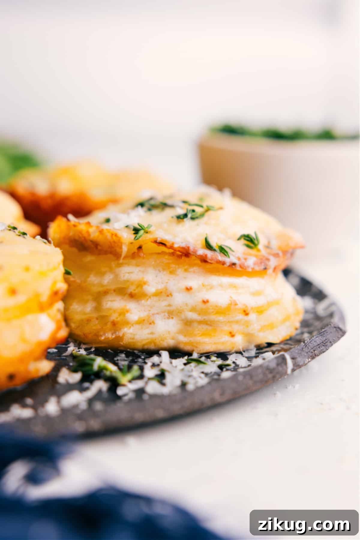 Irresistible Cheesy Potato Stacks Recipe Golden brown potato stacks recipe fresh from the oven, topped with melted Gruyere cheese and a sprinkle of fresh thyme, ready to be served.
