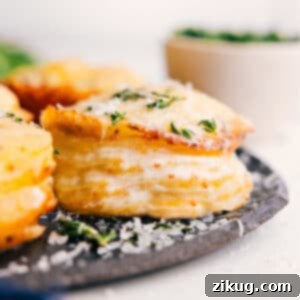 Close-up of baked Potato Stacks with golden cheese and fresh thyme garnish.