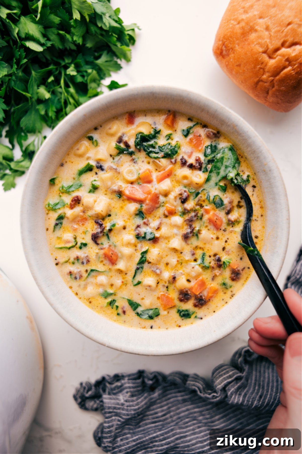 The Ultimate Comfort Food: Creamy Parmesan Italian Sausage Soup for a Cozy Meal A steaming bowl of Creamy Parmesan Italian Sausage Soup, garnished with fresh parsley, served alongside crusty bread on a rustic table, ready to be enjoyed as the ultimate comfort food for a cozy meal.
