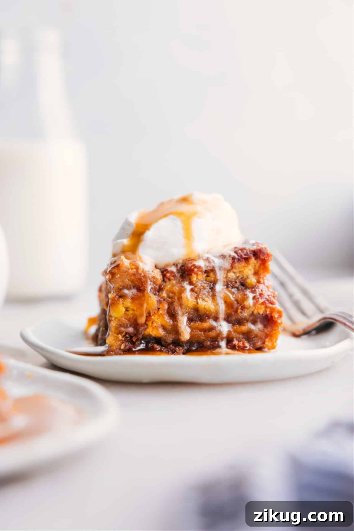 Warm Bread Pudding Slice with Ice Cream - A Delectable Dessert A perfectly baked slice of bread pudding, golden brown on top, served warm in a white bowl and generously topped with a dollop of vanilla bean ice cream. The creamy texture and inviting aroma make it a delectable dessert.