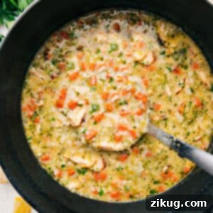 A top-down view of Greek Lemon Soup in a bowl, with a spoon ready to serve. The soup is garnished with fresh dill and a lemon slice, showcasing its inviting golden color and creamy texture.