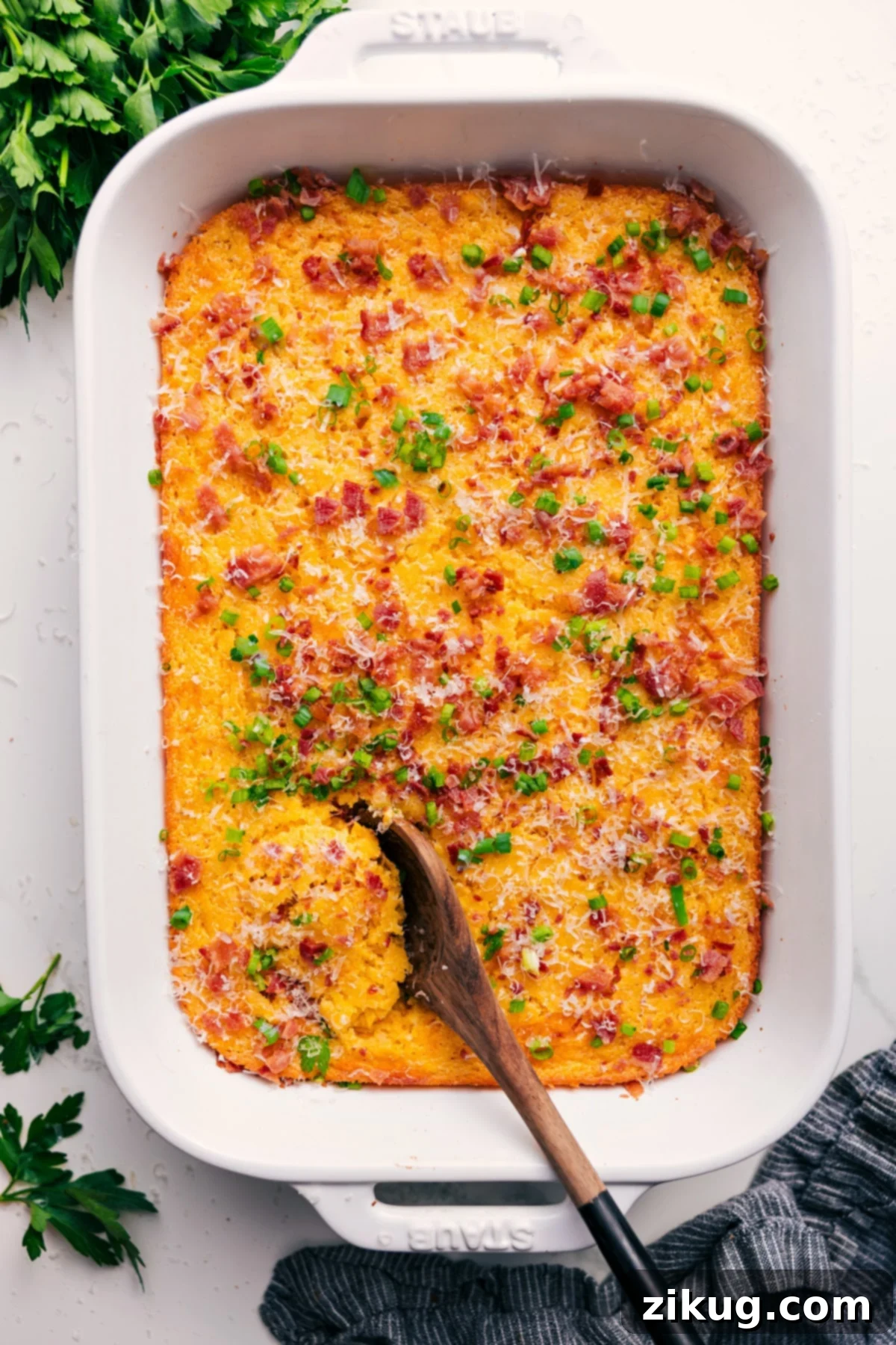 Irresistibly Creamy Corn Pudding Casserole A golden-brown Corn Pudding Casserole in a baking dish, beautifully garnished with melted cheese, vibrant green onions, and crispy bacon bits, ready to be served.
