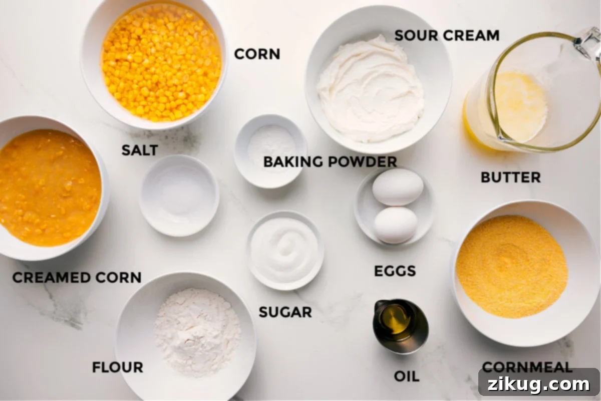Essential Ingredients for the Best Corn Pudding All the essential ingredients for making this corn pudding casserole, meticulously prepped and laid out for easy assembly, including creamed corn, whole kernel corn (undrained), salt, all-purpose flour, baking powder, granulated sugar, sour cream, large eggs, olive oil, cornmeal, and melted unsalted butter.