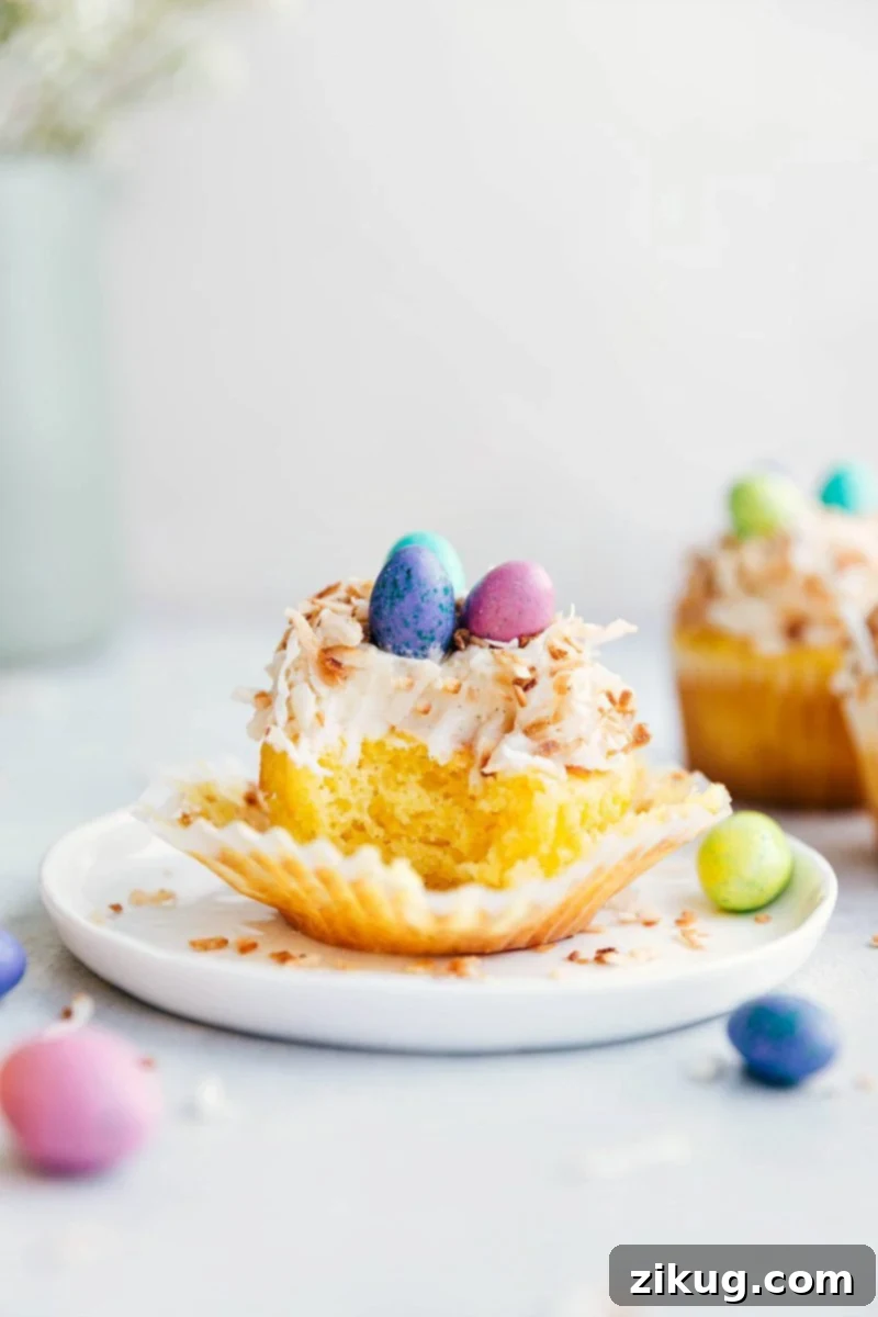 A charming close-up of an Easter cupcake with a bite taken out, revealing its moist texture, with other decorated cupcakes in the background.