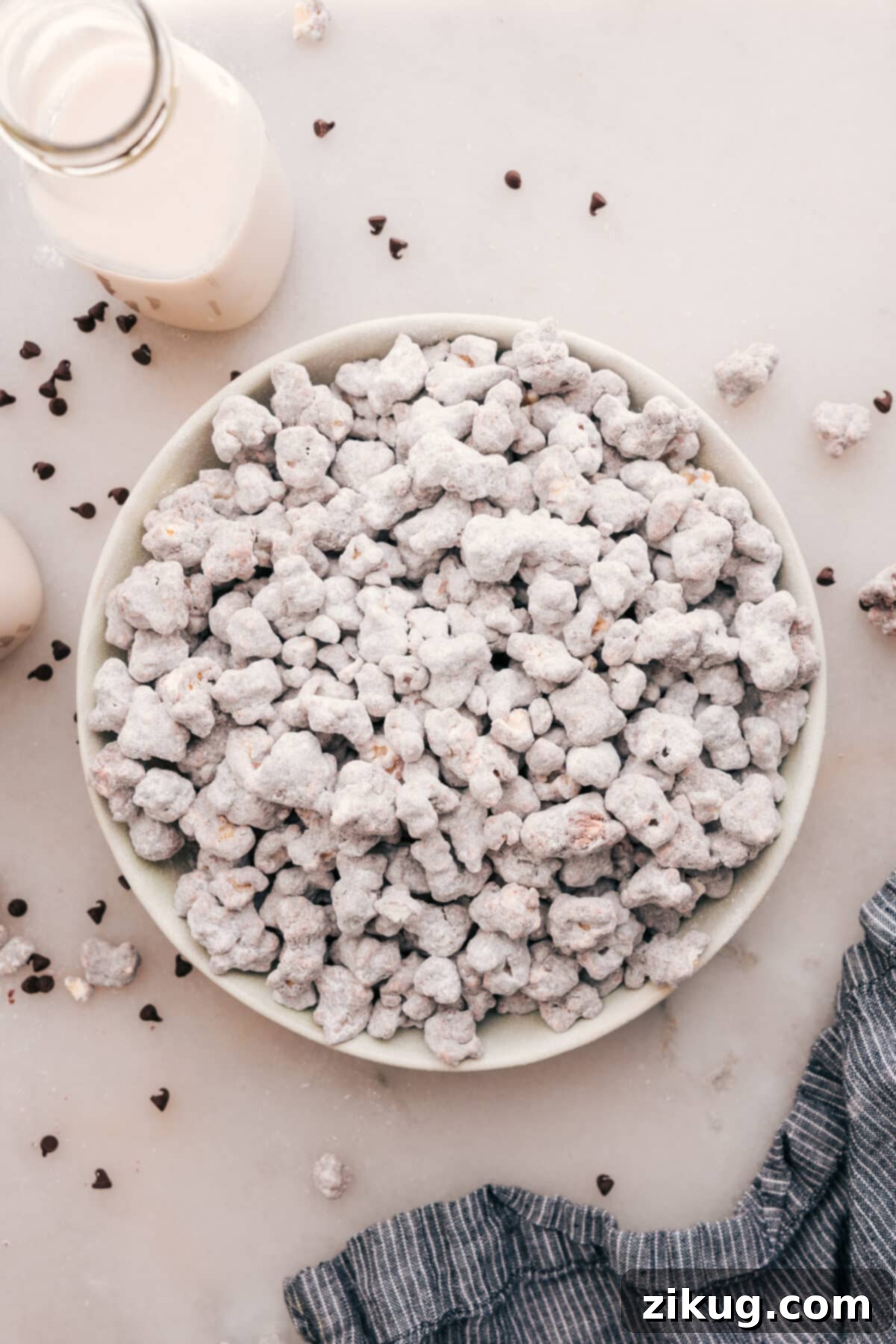 A bowl filled with delicious Popcorn Puppy Chow, coated in chocolate, peanut butter, and powdered sugar, ready for snacking.