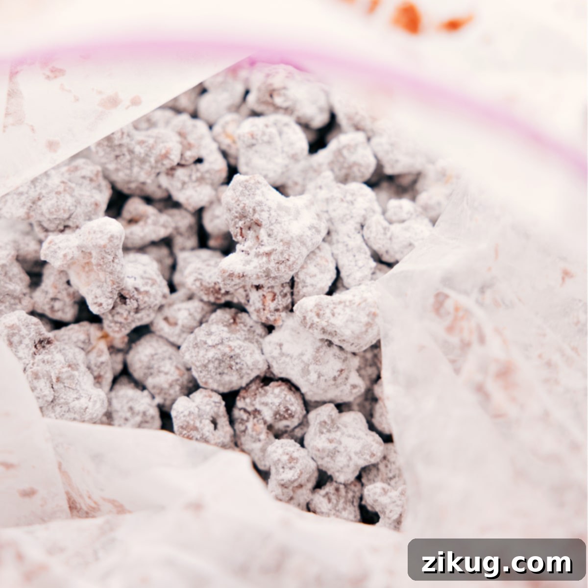 The process of shaking the Popcorn Puppy Chow in a resealable bag with powdered sugar to achieve a perfectly even and sweet coating.